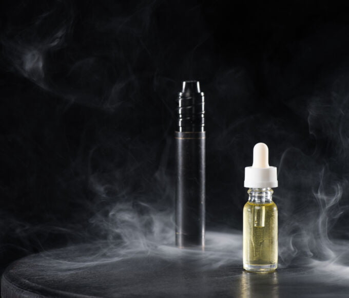 electronic cigarette and liquid with clouds of smoke on dark background